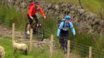 Tamina und Tour-Guide Lewis fahren mit Mountainbikes einen felsigen Pfad hinab