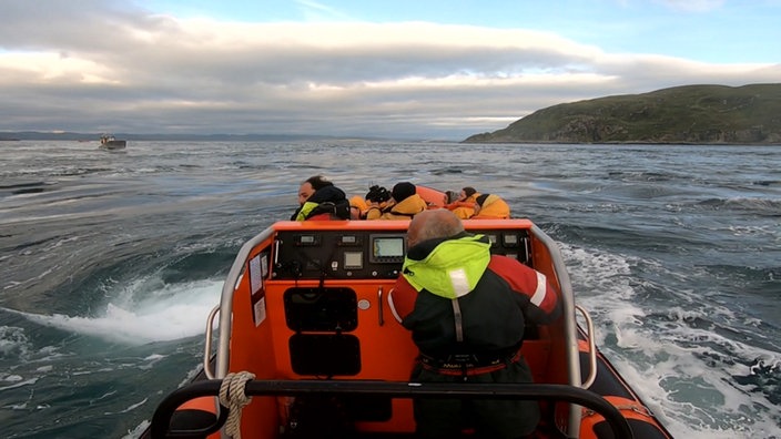 Blick über ein mit mehreren Personen besetztes Schnellboot auf bewegtes Meerwasser