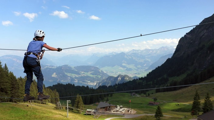 Person mit Kletterausrüstung auf einem Seil