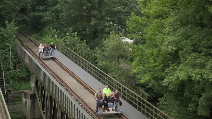 Zwei Draisinen auf einer Strecke über eine Brücke