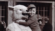 Ein als Eisbär verkleideter Mensch hat einen Jungen auf dem Arm.