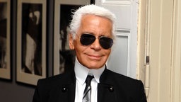 Porträtaufnahme von Karl Lagerfeld, im Hintergund Schwarz-Weiß-Fotografien.