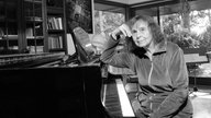 Schwarzweißaufnahme von 2016: Sofia Gubaidulina stützt ihren Kopf auf ein Klavier.