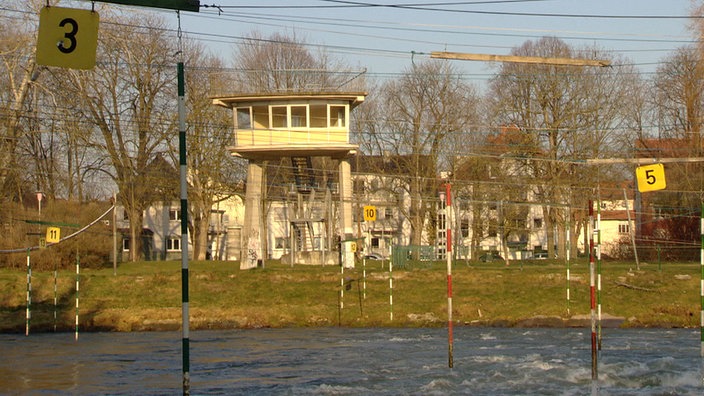 Tagsüber dient er als Schiedsrichterturm für die Kanustrecke, ein schmuckloser Zweckbau aus den 1960er Jahren. 