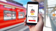 Eine Hand hält ein Handy mit der Deutschlandticket-App