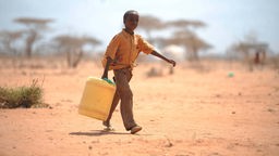 Junge in Somalia trägt einen Kanister mit Wasser. 