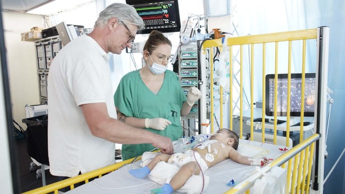 Jörg Gattenlöhner von Kinderherzen e.V. mit Krankenschwester und operierten Kleinkind. 