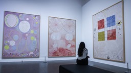 Eine Besucherin betrachtet die Gemälde von Hilma af Klint in der Ausstellung "Hilma af Klint und Wassily Kandinsky" in Düsseldorf.