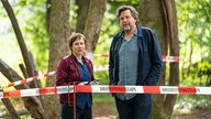 Eva Löbau und Hans-Jochen Wagner stehen bei den Dreharbeiten zu "Tatort: Ad Acta" (undatierte Filmszene) zwischen Bäumen.