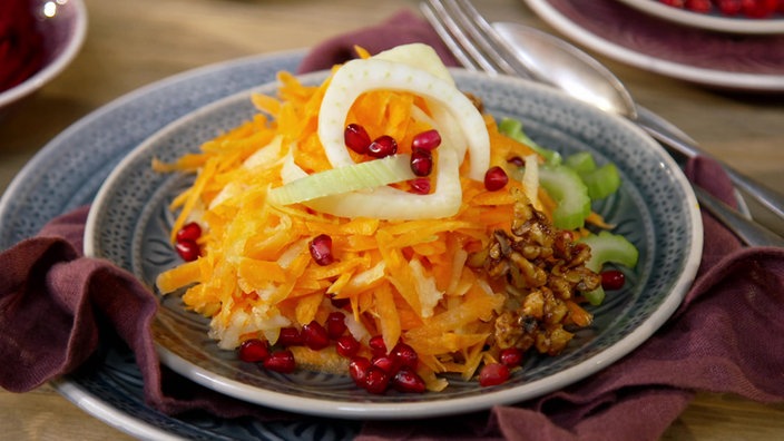 Das Bild zeigt das fertige Gericht Apfel-Möhren-Salat mit fruchtigem Orangendressing, kandierten Walnüssen und Granatapfelkernen.