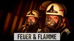 Feuerwehrmänner vor einer brennenden Wand