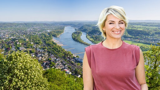 Eine blonde Frau lächelt in die Kamera, hinter ihr eine Flusslandschaft