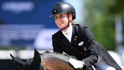 Jessica von Bredow-Werndl sitzt auf einem Pferd und lächelt