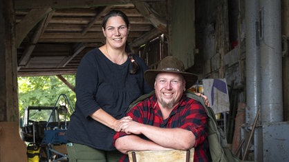 Helmut (r) sitzend auf einem Stuhl mit seiner Frau Cindy (l) stehend in ihrer Scheune.