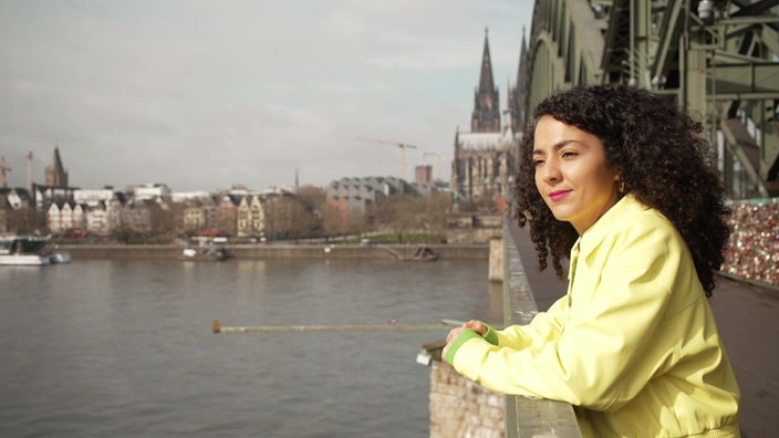 Siham El-Maimouni steht auf der Hohenzollernbrücke und blickt auf den Rhein