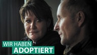 Eine Frau und ein Mann schauen sich an, auf dem Bild der Schriftzug "Wir haben adoptiert"