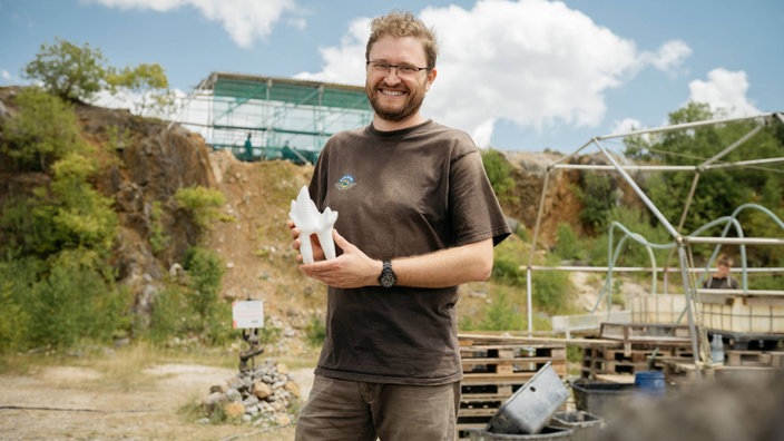 LWL-Wissenschaftler Dr. Achim Schwermann mit einem Modell des 1,6 Millimeter großen Backenzahns, den er in Balve gefunden hat.