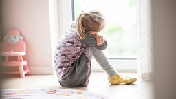 Mädchen sitzt traurig vor dem Fenster