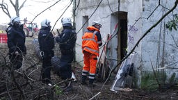 Lützerath: Polizei und Rettungssanitäter stehen am Eingang eines Hauses, unter dem sich der Eingang zu einem Tunnelsystem befindet