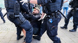 Demonstrant wird von Polizist weggetragen