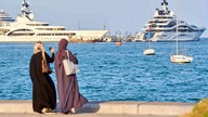 Frauen stehen am Meer und tragen Kleider