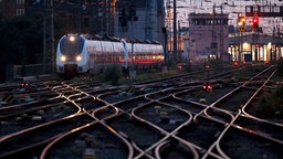 Gleise am Kölner Hbf. Weiter hinten eine Bahn und der Bahnhof