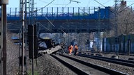  Mitarbeiter der Deutschen Bahn begutachten einen aus den Gleisen gesprungenen Güterwaggon am Bahnhof Langerfeld.