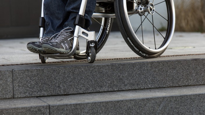 Rollstuhl steht am oberen Rand einer Treppe