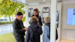 Ein WDR-Stand, an dem sich Menschen aus Warburg mit einer WDR-Reporterin unterhalten.