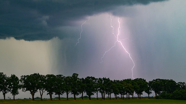 Ein Blitz leuchtet am späten Abend über der Landschaft auf.