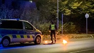  Ein Polizist steht bei dem Feuer vor einem Streifenwagen.