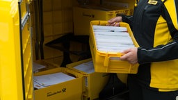 Briefträger packt Kisten mit Briefen