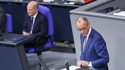 CDU-Chef Friedrich Merz steht am Rednerpult im Bundestag. Im Hintergrund Bundeskanzler Olaf Scholz.