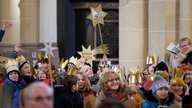 Sternsinger erheben ihre Sternenschilder