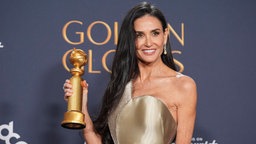 Demi Moore bei den Golden Globes im goldenen Kleid auf dem roten Teppich