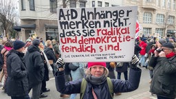 Anke hält auf der Demonstration gegen die AfD in Düsseldorf ein Schild in die Luft