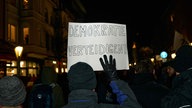 Auf einer Demo in Essen hält eine Person ein Schild mit der Aufschrift: "Demokratie verteidigen"