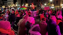 Menschen stehen mit Fahnen und Plakaten in Soest auf dem Marktplatz.