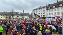 Demonstrierende Menschen mit bunten Flaggen und Schildern