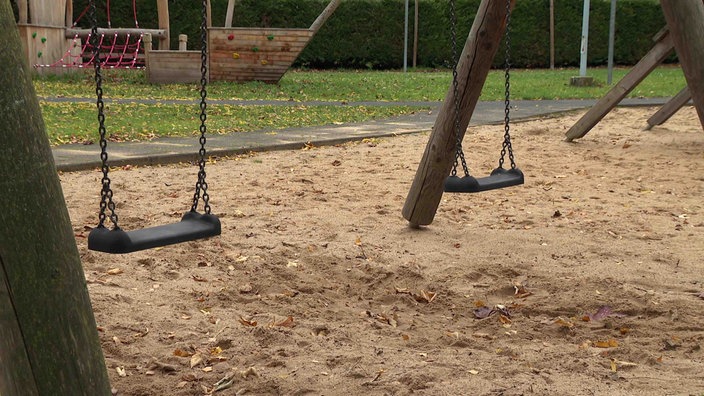 Zwei leere Schaukeln auf einem Schulhof