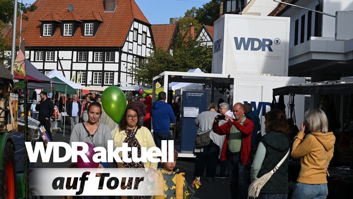 Mehrere Besucher laufen durch die Straßen von Ennigerloh, ein Aufbau mit WDR Logo ist rechts im Bild zu sehen 