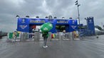 Ein Fan steht im Regen vor der Fan Zone Düsseldorf