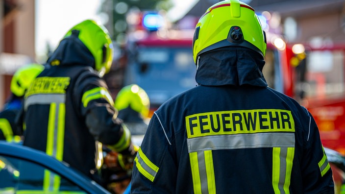 Feuerwehrleute stehen während einer Übung um ein Auto