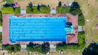 Drohnenaufnahme von Badegästen in dem im Stadtpark gelegenen Underbergbad.