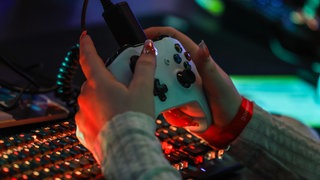 Eine Frau hält einen Gaming Controller in ihren Händen 