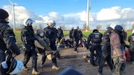 Aktivisten auf der nördlichen Zufahrt zum Tagebau Garzweiler werden von Polizisten abgeführt