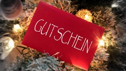 roter Briefumschlag mit Aufschrift Gutschein liegt zwischen Weihnachtsdekoration