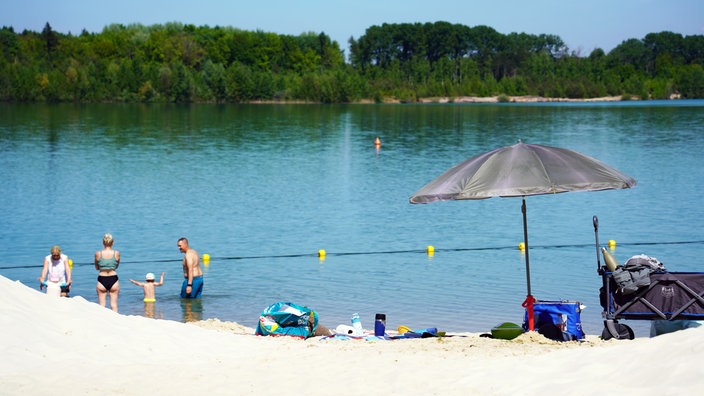 Menschen sonnen sich und baden im Wasser.