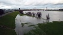 Eine Wiese am Rhein ist überflutet, im Hintergrund ist eine Brücke zu sehen