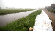 Sandsäcke liegen in Isselburg (Nordrhein-Westfalen) auf einem Deich.